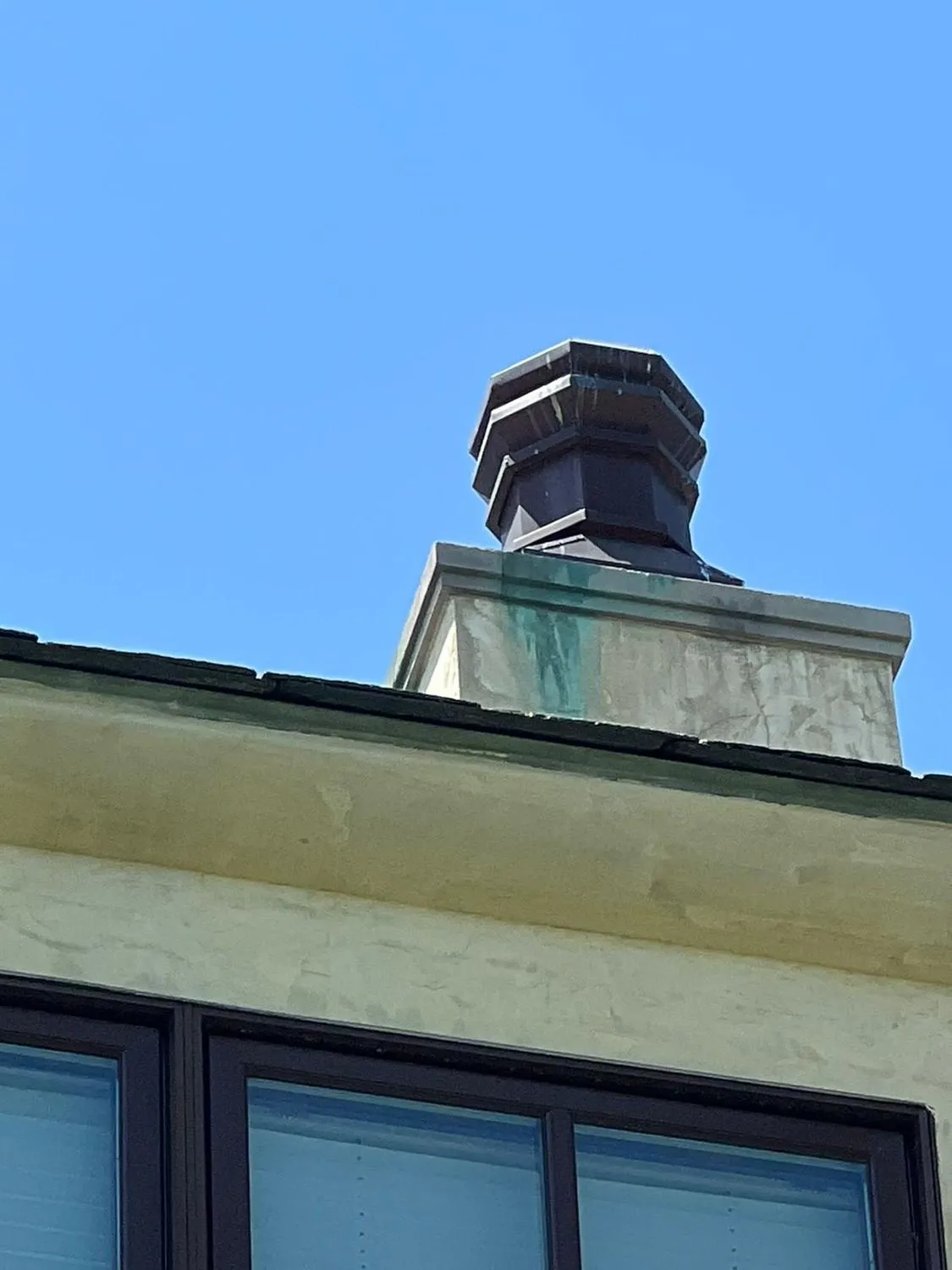 Black chimney cap on chase above modern house