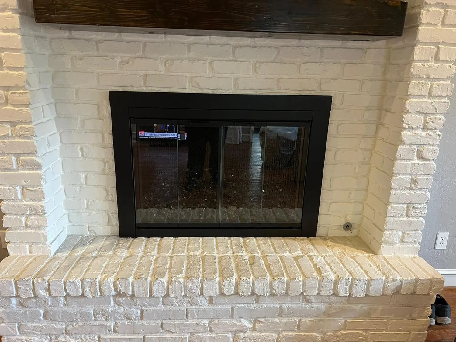 Black glass-door insert installed in white brick fireplace