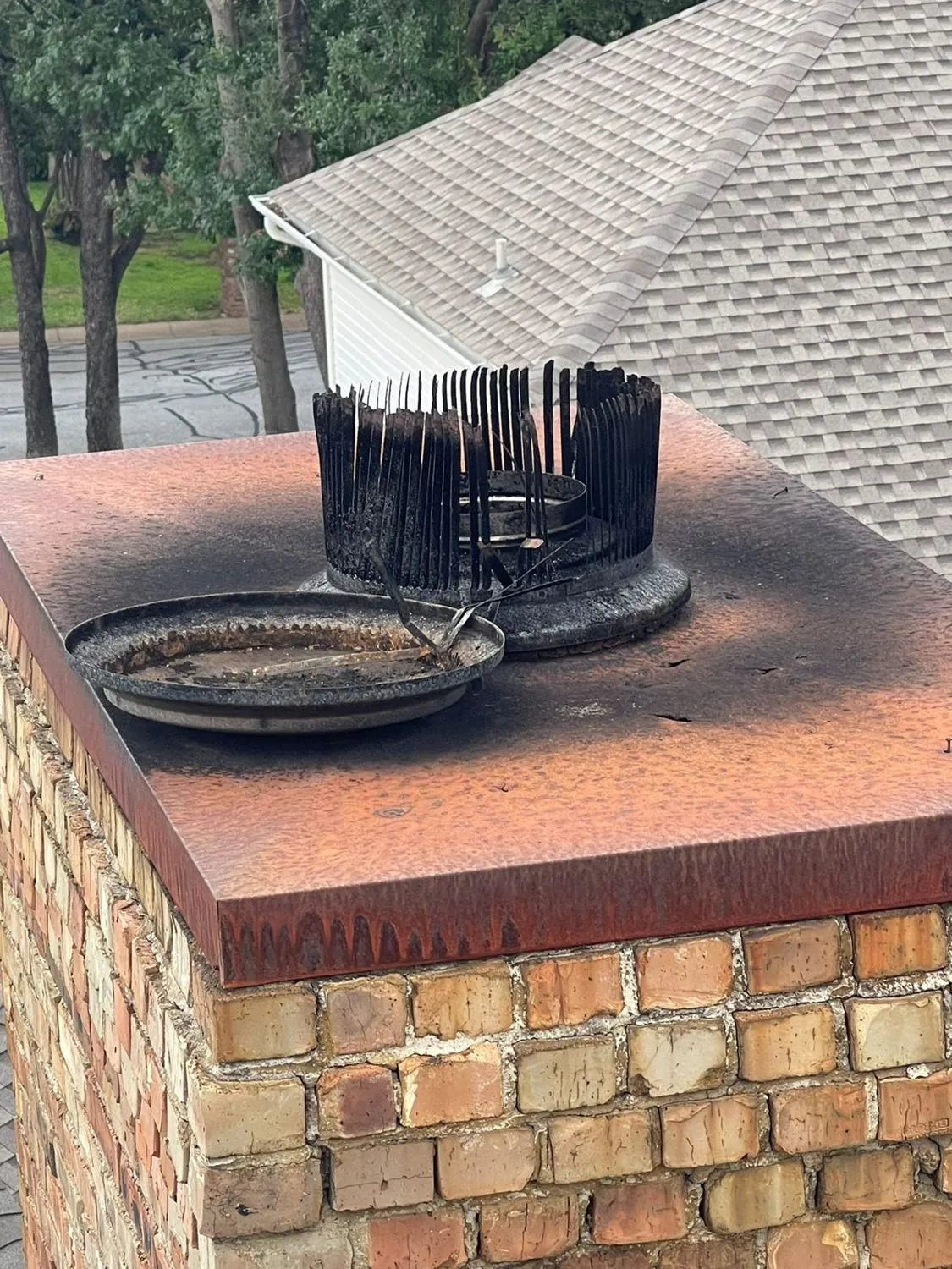 Brick chimney crown with bird spikes and rust staining