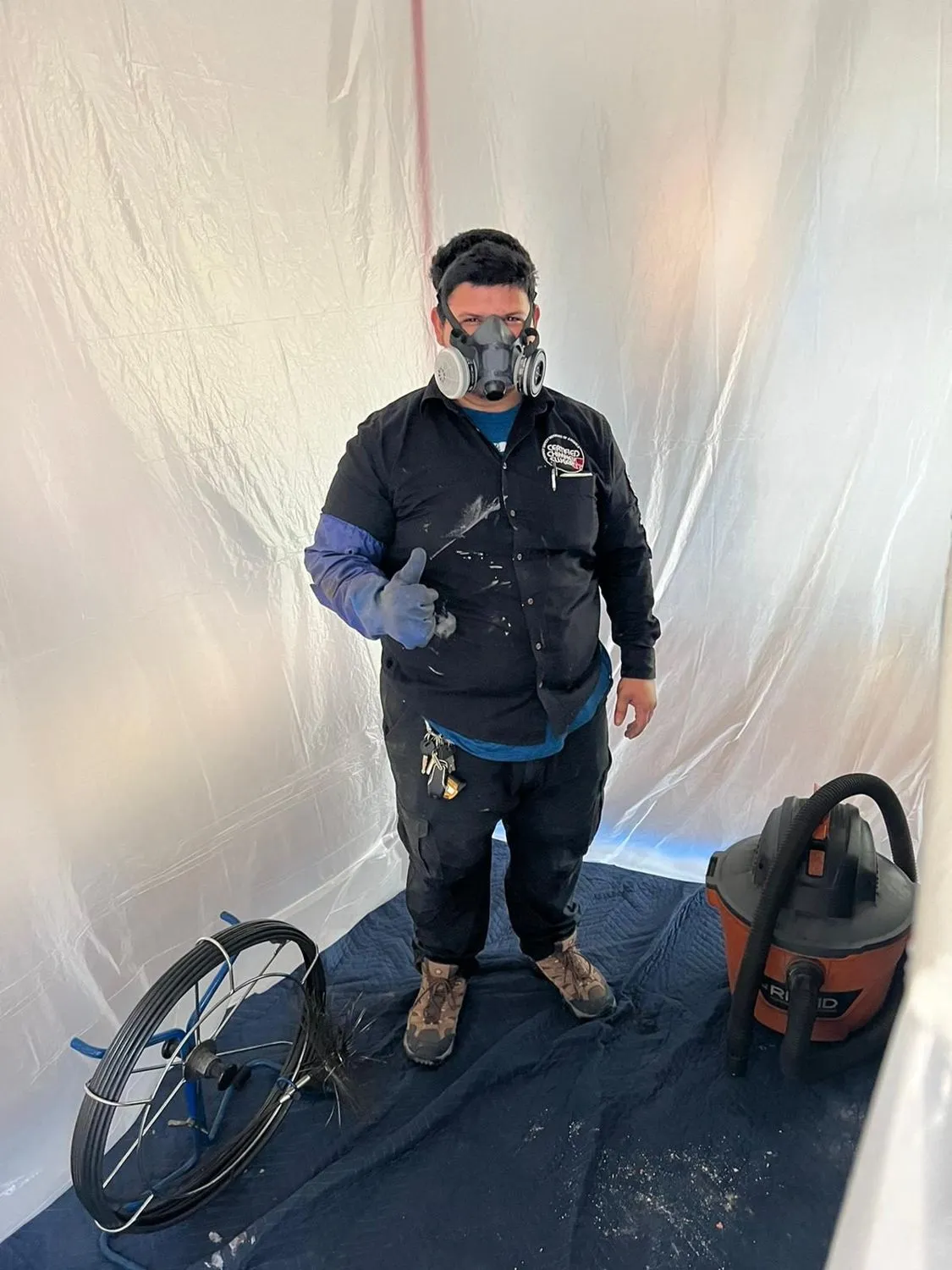 Chimney sweep in respirator giving thumbs up with equipment