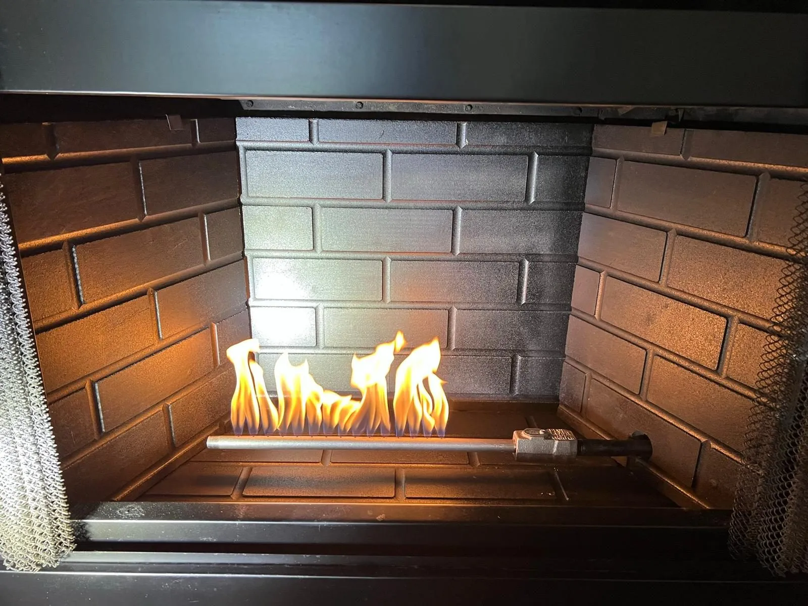 Gas log flames burning inside red brick firebox