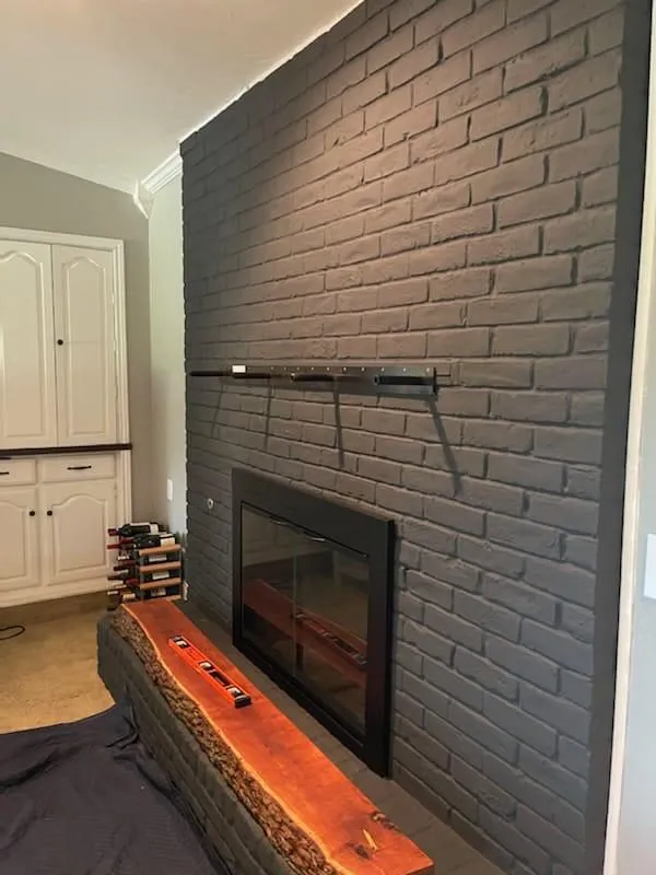 Gray brick fireplace with new live-edge wood mantel
