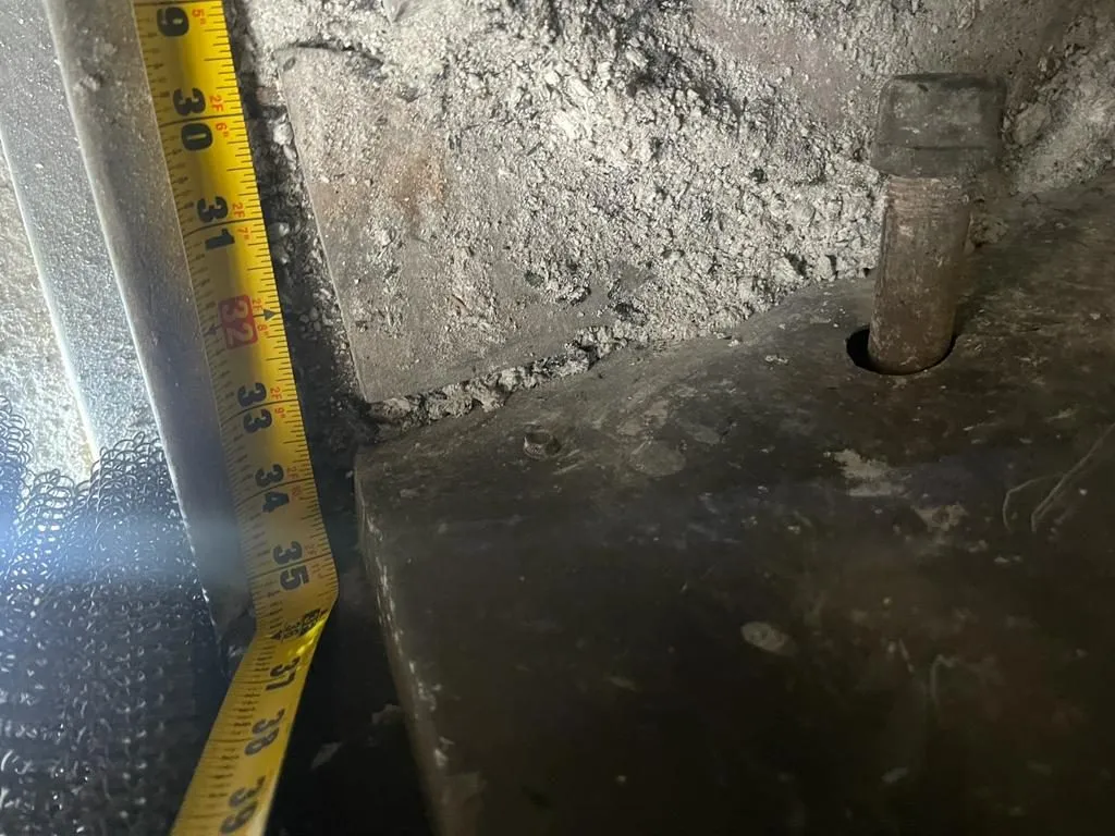 Technician measuring sooty masonry smoke chamber wall during fireplace inspection