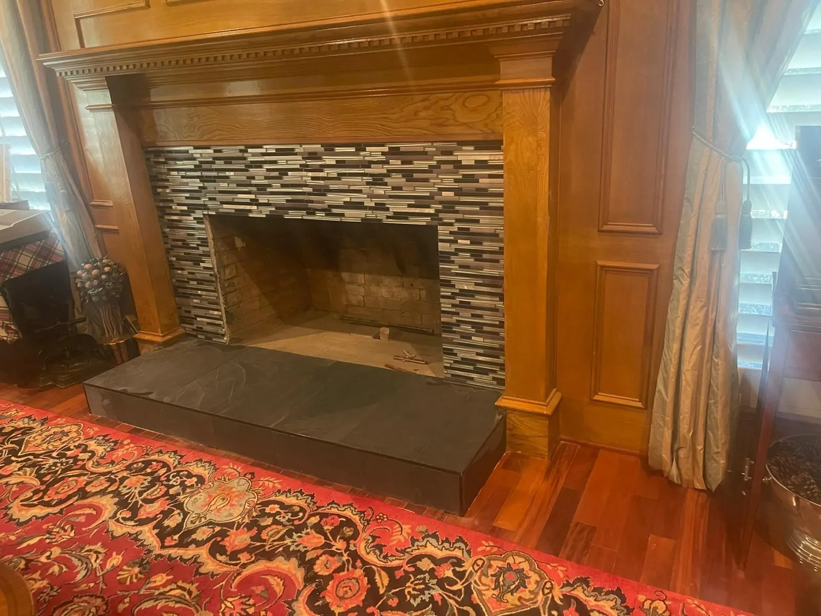 Finished stacked stone fireplace with dark tile hearth