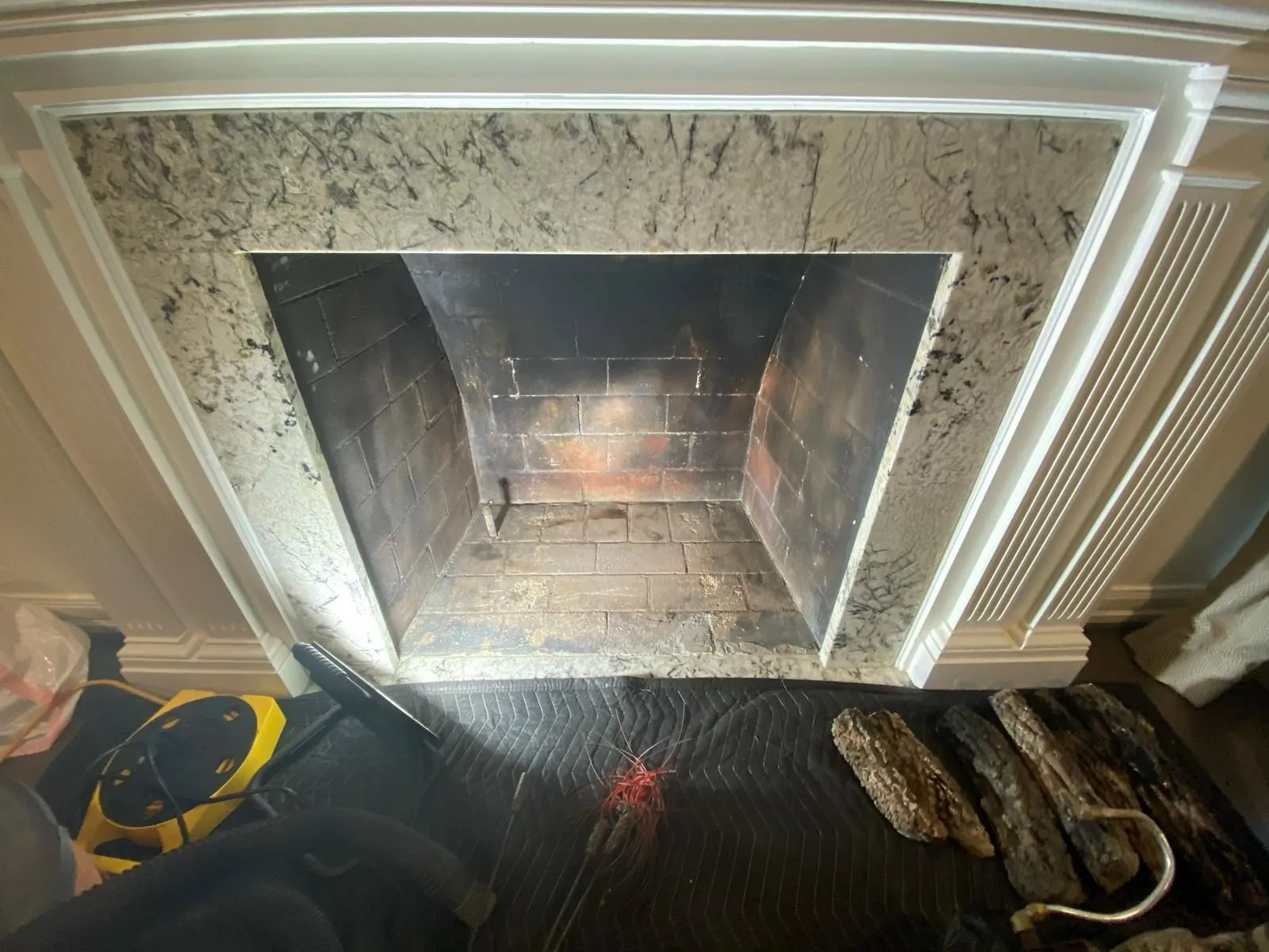 Technician performing camera inspection inside granite surround fireplace