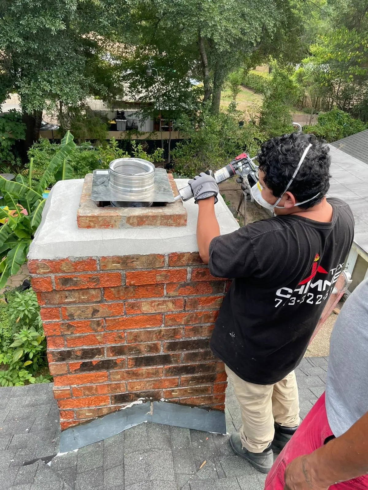 Technician sealing cap on red brick chimney