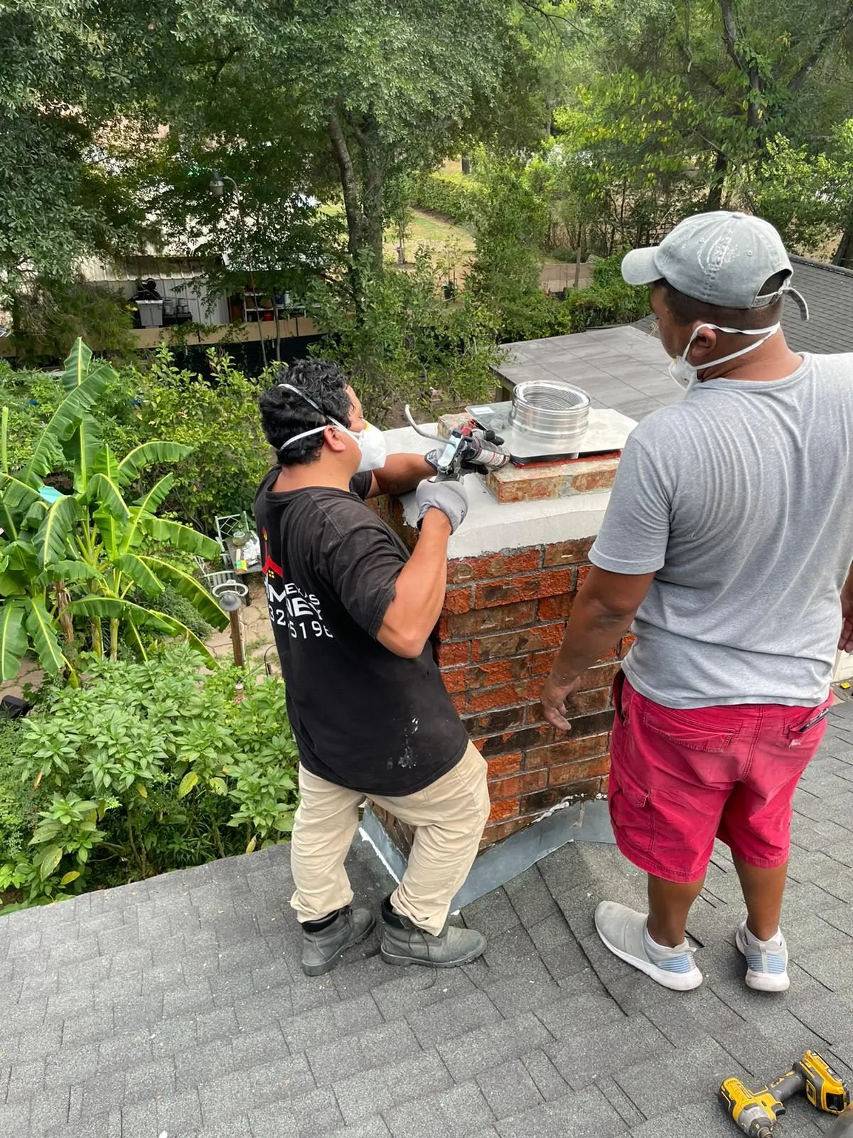 Two technicians rebuilding chimney crown on roof
