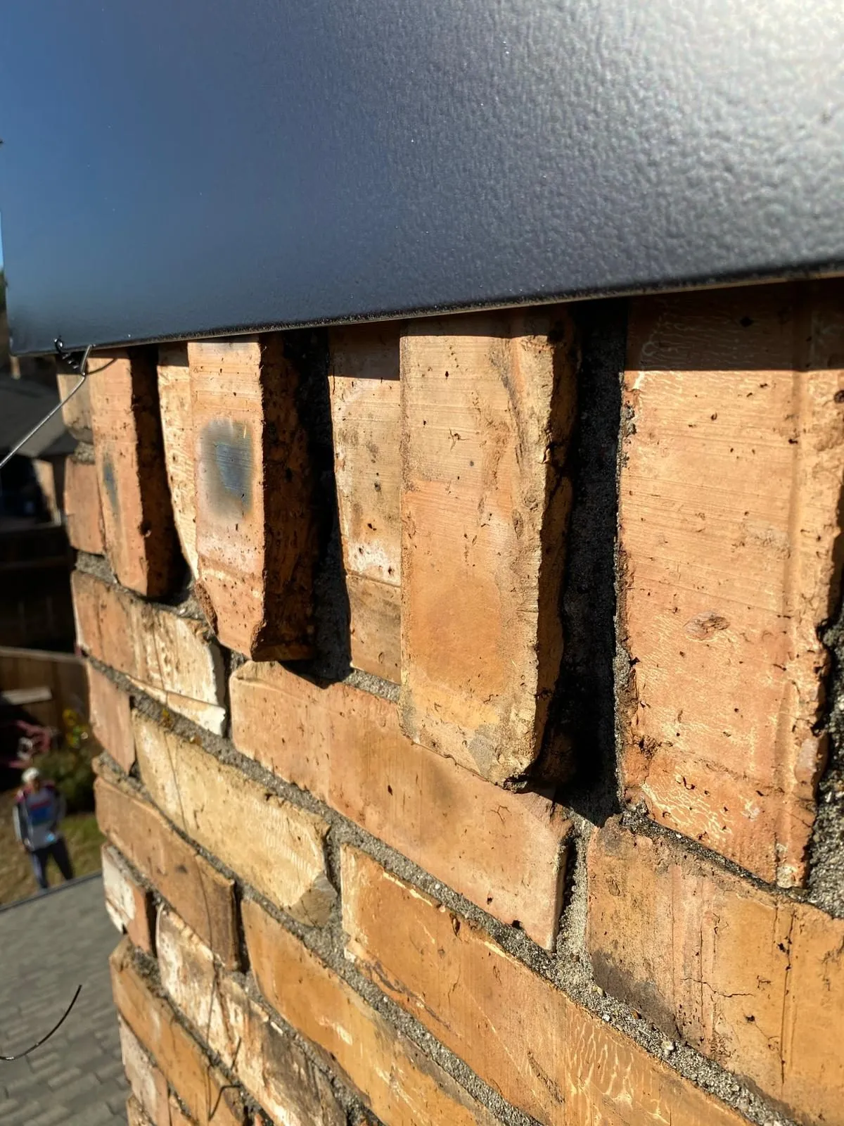 Weathered red brick chimney stack with damaged mortar joints