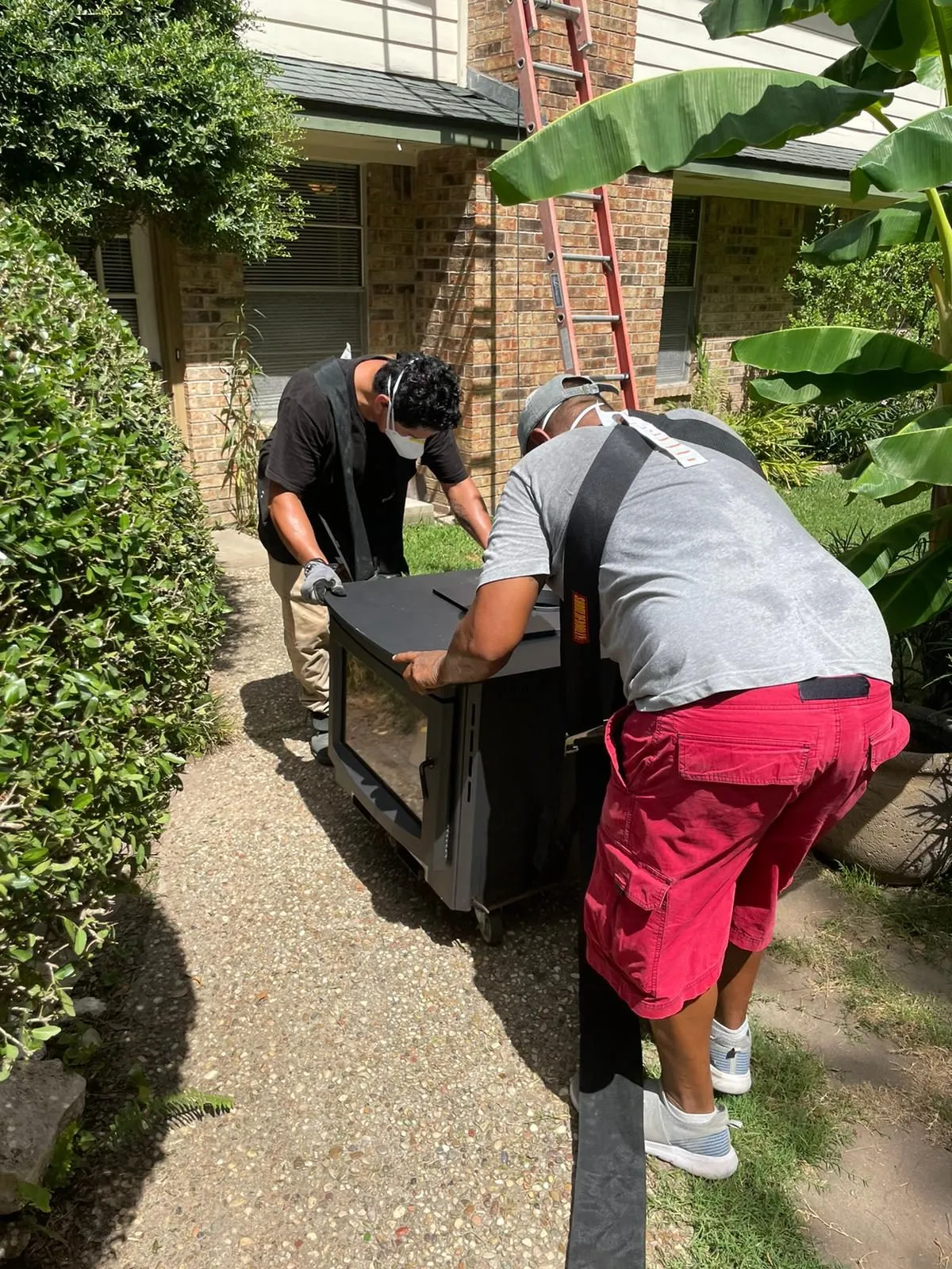 Two workers carrying new fireplace insert into home