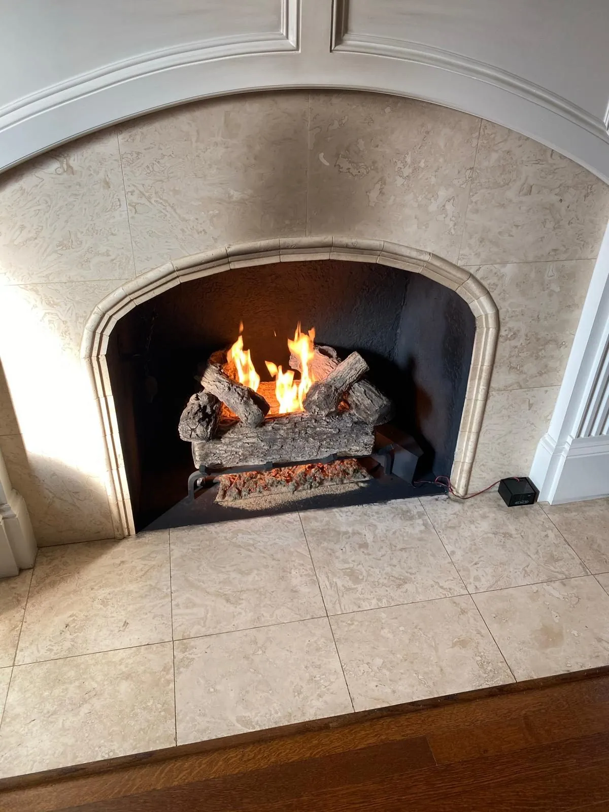 Arched stone fireplace with gas logs burning brightly