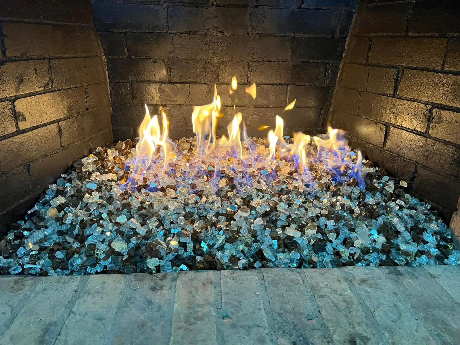 Flames dancing over blue fire glass in firebox