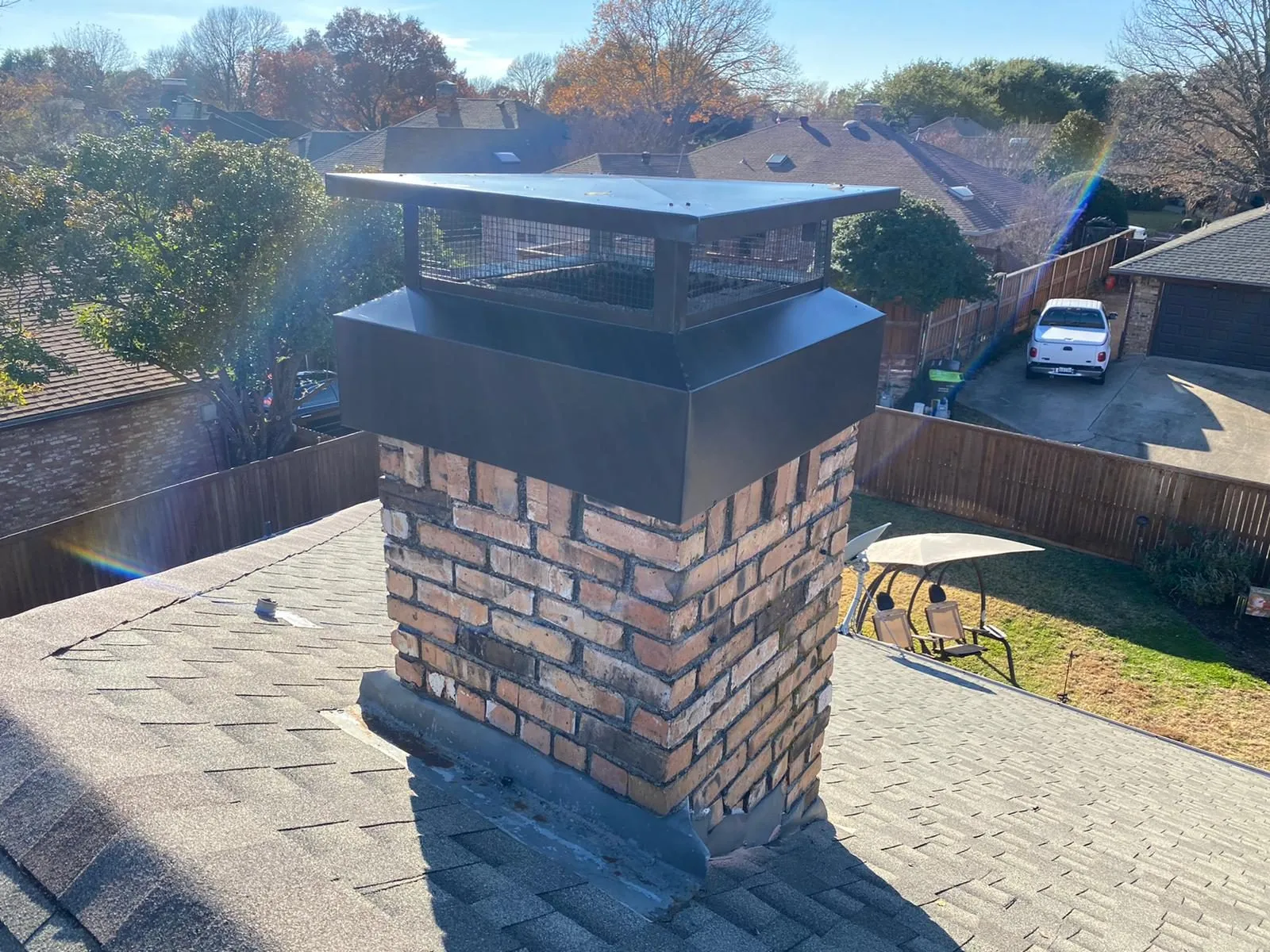 Red brick chimney with a new black cap in afternoon light